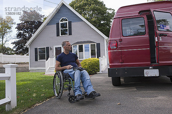 Ein querschnittsgelähmter Mann im Rollstuhl steigt mit einer Fernbedienung in seinen Lieferwagen ein