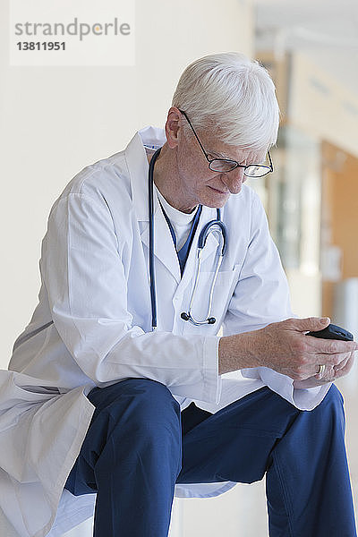 Arzt liest eine Textnachricht auf dem Mobiltelefon