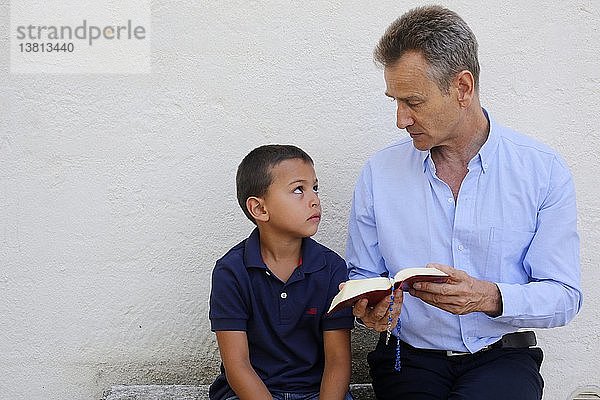 Ein Vater liest seinem Sohn aus der Bibel vor.