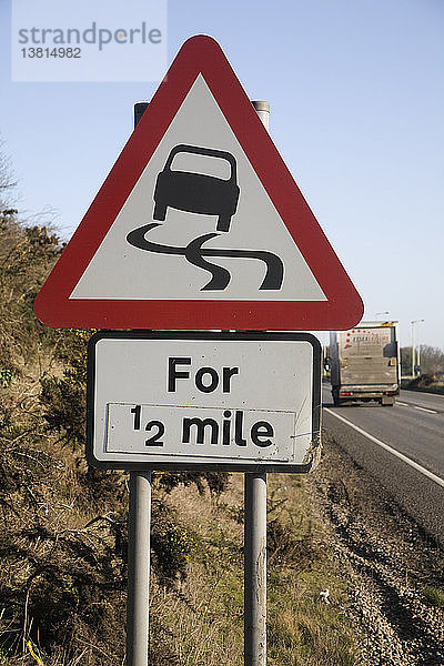 Rotes dreieckiges Straßenschild  das auf einer halben Meile vor glatter Fahrbahn warnt  UK