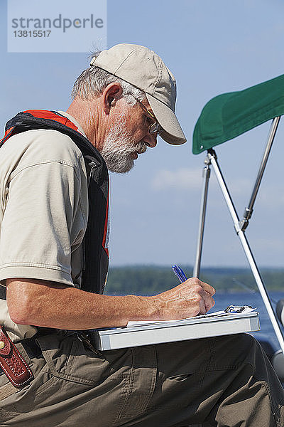 Ein Bauingenieur auf einem Dienstboot bereitet sich auf die Entnahme von Wasserproben aus dem Stausee vor