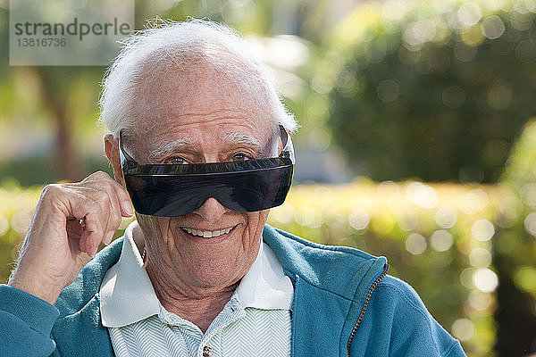 Porträt eines älteren Mannes  der eine dunkle Brille mit grauem Star trägt