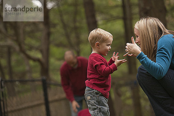 Frau gebärdet das Wort ´Play´ in amerikanischer Zeichensprache  während sie mit ihrem Sohn in einem Park kommuniziert