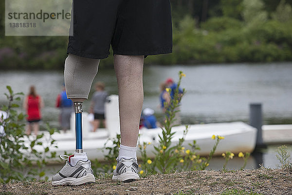 Ein Mann mit einer Beinprothese steht auf dem Steg und beobachtet das Bootsrennen