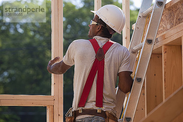 Spanischer Zimmermann auf einer Leiter  der den Dachstuhl eines im Bau befindlichen Hauses prüft