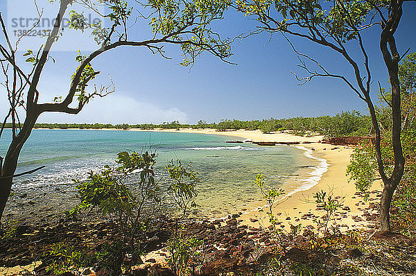 Der Strand der Coral Bay  eine unveränderte und unverschmutzte Umgebung  in der Küsten- und ökologische Prozesse (z. B. Brände in der Trockenzeit in der Ferne) auf natürliche Weise ablaufen können  Garig Ganuk Barlu National Park  Cobourg Peninsula  Arnhem Land  Northern Territory  Australien