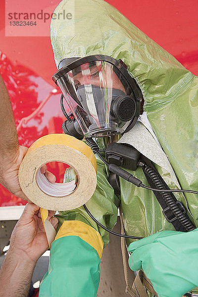 HazMat-Feuerwehrmann hilft seinem Kollegen beim Ankleben von Schutzhandschuhen