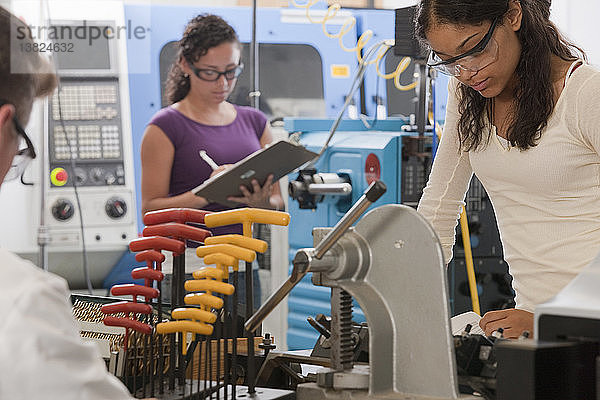 Ingenieurprofessor und Studenten arbeiten an einer CNC-Maschine