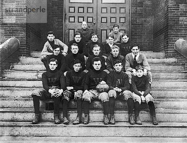 Vereinigte Staaten: 1909 Ein Porträt einer Highschool-Football-Mannschaft  die auf den Stufen der Schule sitzt.