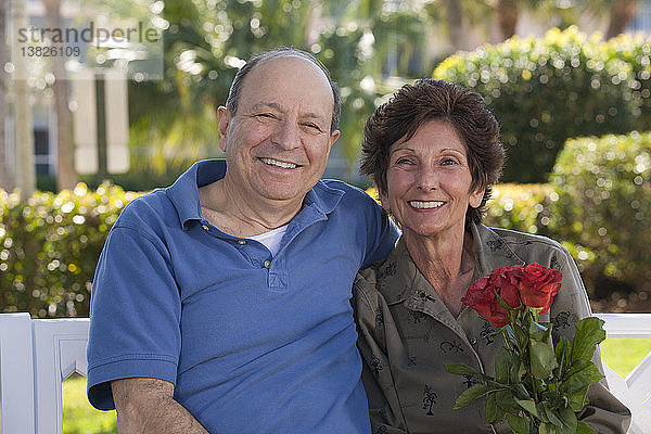 Porträt eines lächelnden älteren Paares mit einer Valentinsrose
