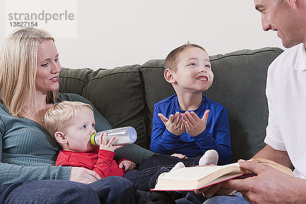 Junge gebärdet das Wort ´Book´ in amerikanischer Zeichensprache  während er mit seinen Eltern lernt