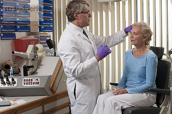 Augenarzt  der einem Patienten mit einem Eisbeutel eine Botox-Injektion verabreicht