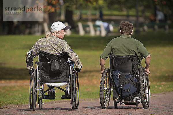 Zwei Kriegsveteranen in Rollstühlen in einem Park