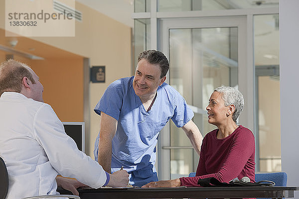 Arzt und Krankenpfleger beraten sich mit einem Patienten
