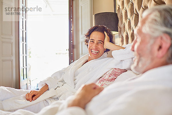 Glückliches  lachendes reifes Paar  das sich auf einem Hotelbett entspannt