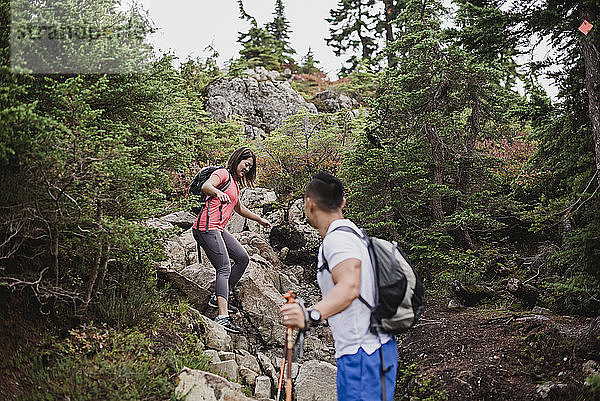 Paar wandert Felsen im Wald hinunter