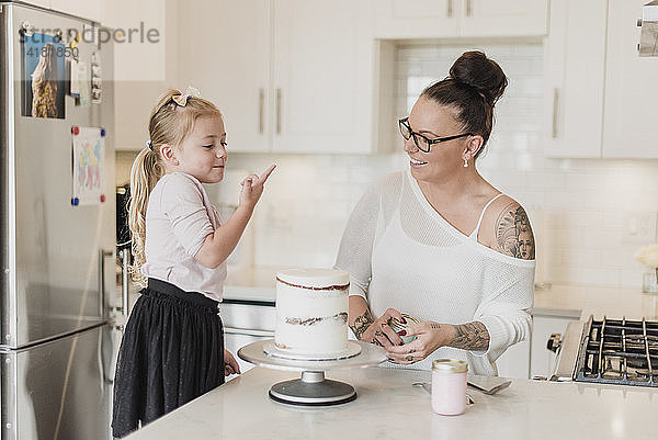 Mutter und Tochter dekorieren Kuchen in der Küche