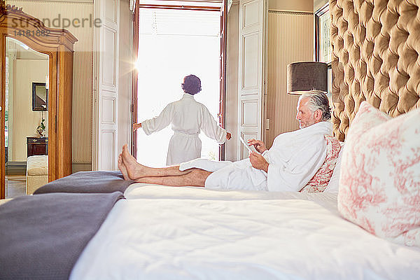 Älteres Paar in Bademänteln entspannt sich im Hotelzimmer