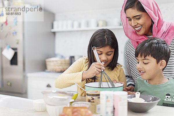 Mutter im Hidschab backt mit Kindern in der Küche