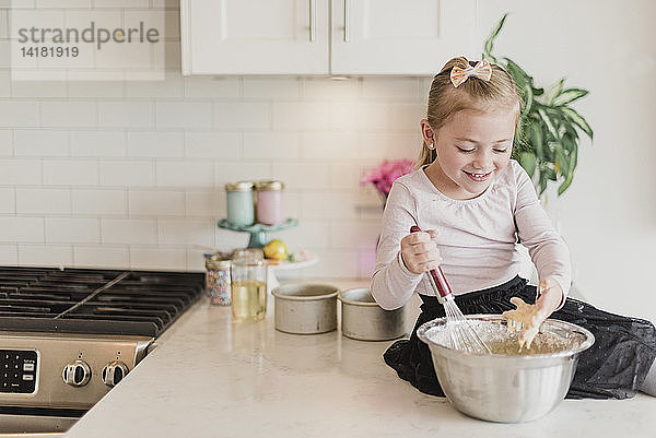 Lächelndes Mädchen beim Backen auf der Küchentheke