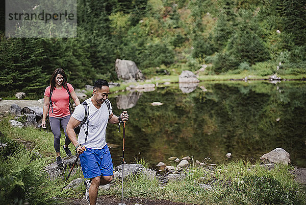 Ehepaar wandert entlang eines Sees im Wald