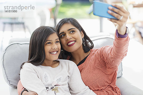 Glückliche Mutter und Tochter nehmen Selfie mit Smartphone im Sessel