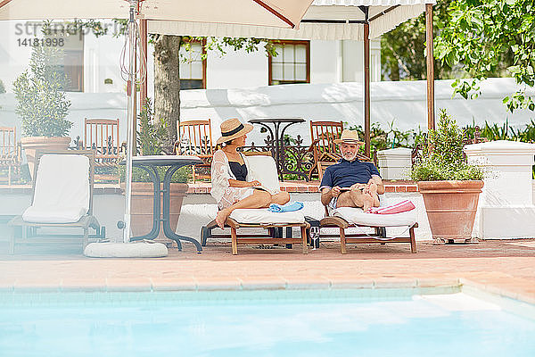 Älteres Paar entspannt sich auf Liegestühlen am Pool des Resorts