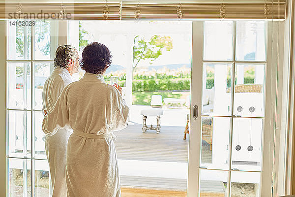 Älteres Paar in Bademänteln an der Terrassentür eines Hotels