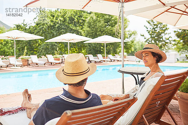 Ehepaar entspannt sich auf Liegestühlen am Pool des Resorts