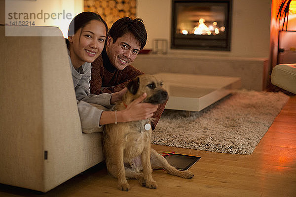 Portrait glückliches Paar mit Hund im Wohnzimmer