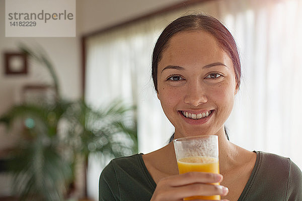 Porträt einer selbstbewussten jungen Frau  die Orangensaft trinkt