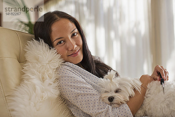 Porträt lächelnde junge Frau  die mit ihrem Hund kuschelt