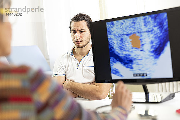 Ein Mann konsultiert eine Ärztin zur Ultraschalluntersuchung der Prostata.