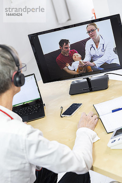 Pädiatrische Videosprechstunde mit einem Arzt und seinem Kollegen in Anwesenheit des Kindes und des Vaters.