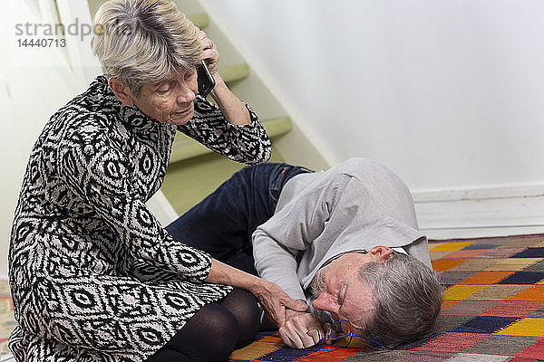 Eine ältere Frau hilft einem älteren Mann  der eine Treppe hinuntergefallen ist.