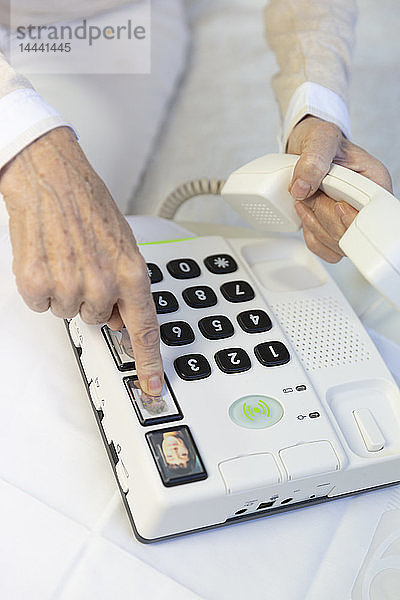 Ältere Frau benutzt ein Telefon mit großen Tasten für ältere Menschen.