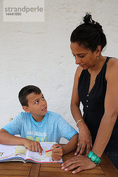 11-jähriger Junge  der von seiner Mutter bei den Hausaufgaben unterstützt wird  in Salento  Italien