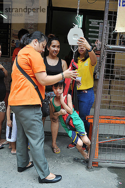 Wiegen eines Kindes in einem Gesundheitszentrum in Manila auf den Philippinen.