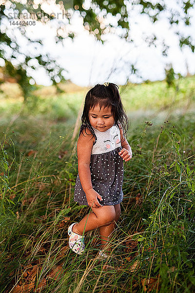 Ein kleines Mädchen  das mit bloßen Beinen im hohen Gras läuft...