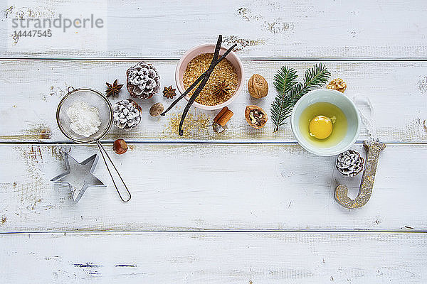 Weihnachtliches Backstilleben mit Zucker  Ei  Mehl  Tannenzweig  Pinienzapfen  Vanillestangen  Sternanis und Nüssen