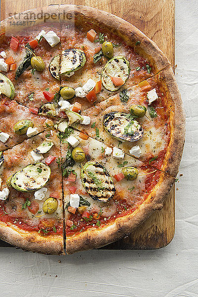 Pizza mit Feta und Gemüse auf einem Holzbrett