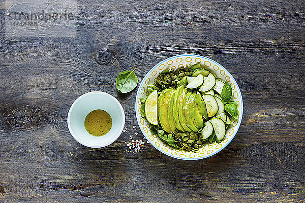 Veganer grüner Sommersalat mit Avocado  Rucola  Gurken und Kürbiskernen und Dressing
