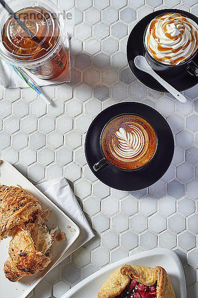 Verschiedene Kaffeegetränke und süßes Gebäck auf einem Tisch in einer Kaffeebar