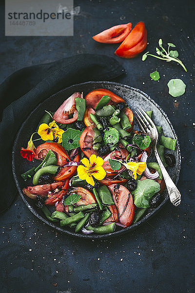 Tomaten- und Bohnensalat mit Blumen in einer grauen Schale