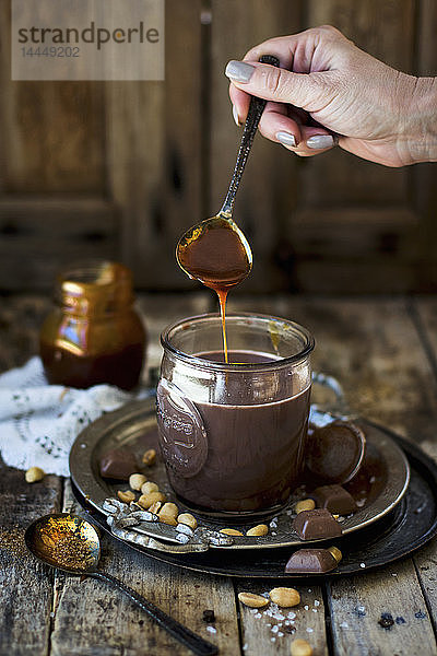 Erdnusskaramell fliesst in Tasse mit heißer Schokolade