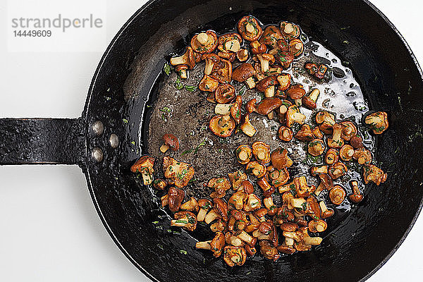 Gemischte Waldpilze in einer Pfanne mit Butter und Kräutern gebraten