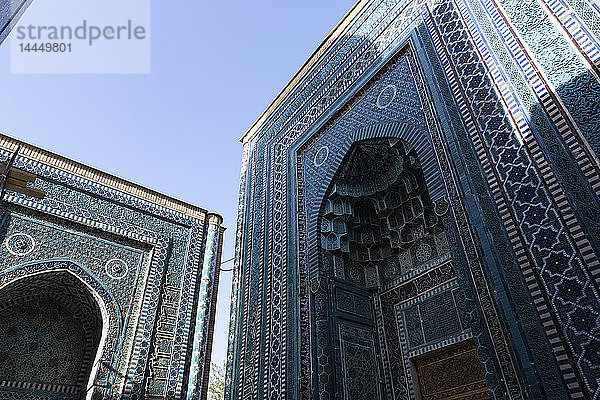 Niedrigwinkelansicht der hohen Bögen eines islamischen Madrasa-Gebäudes mit blau-weiß gemusterten glasierten Kacheln.