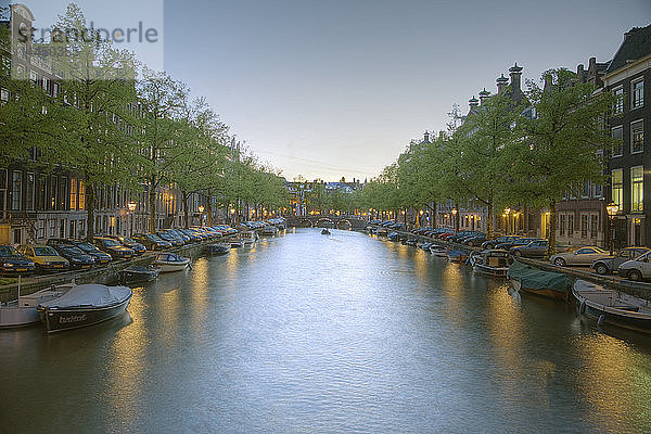 Boote in einem von Bäumen gesäumten Kanal in der Abenddämmerung