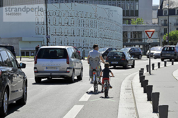 Frankreich  Region Pays de La Loire  Stadt Nantes  Fahrrad fahrende Personen auf einem Radweg neben dem Verkehr.