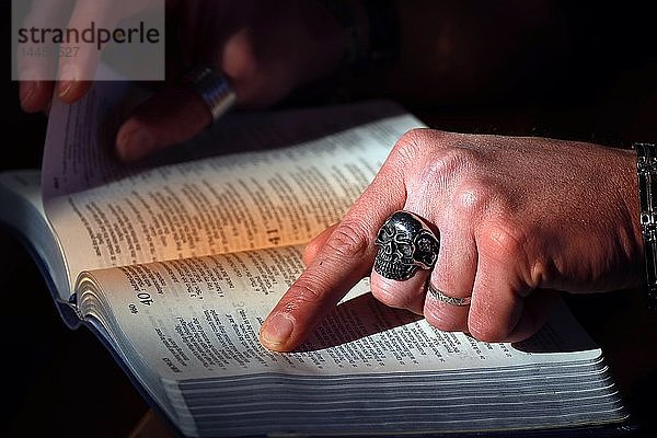 Mann mit Totenkopfring liest die heilige Bibel. Frankreich.